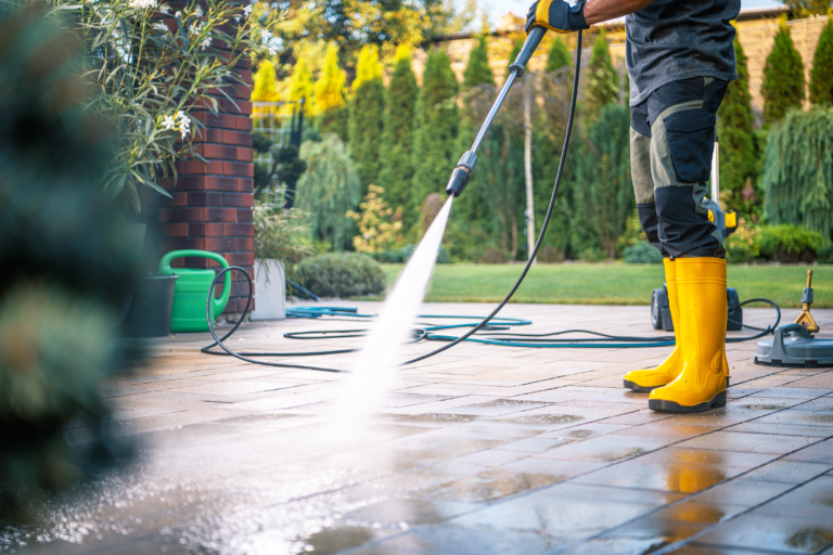 man-in-yellow-boots-pressure-washing-a-patio