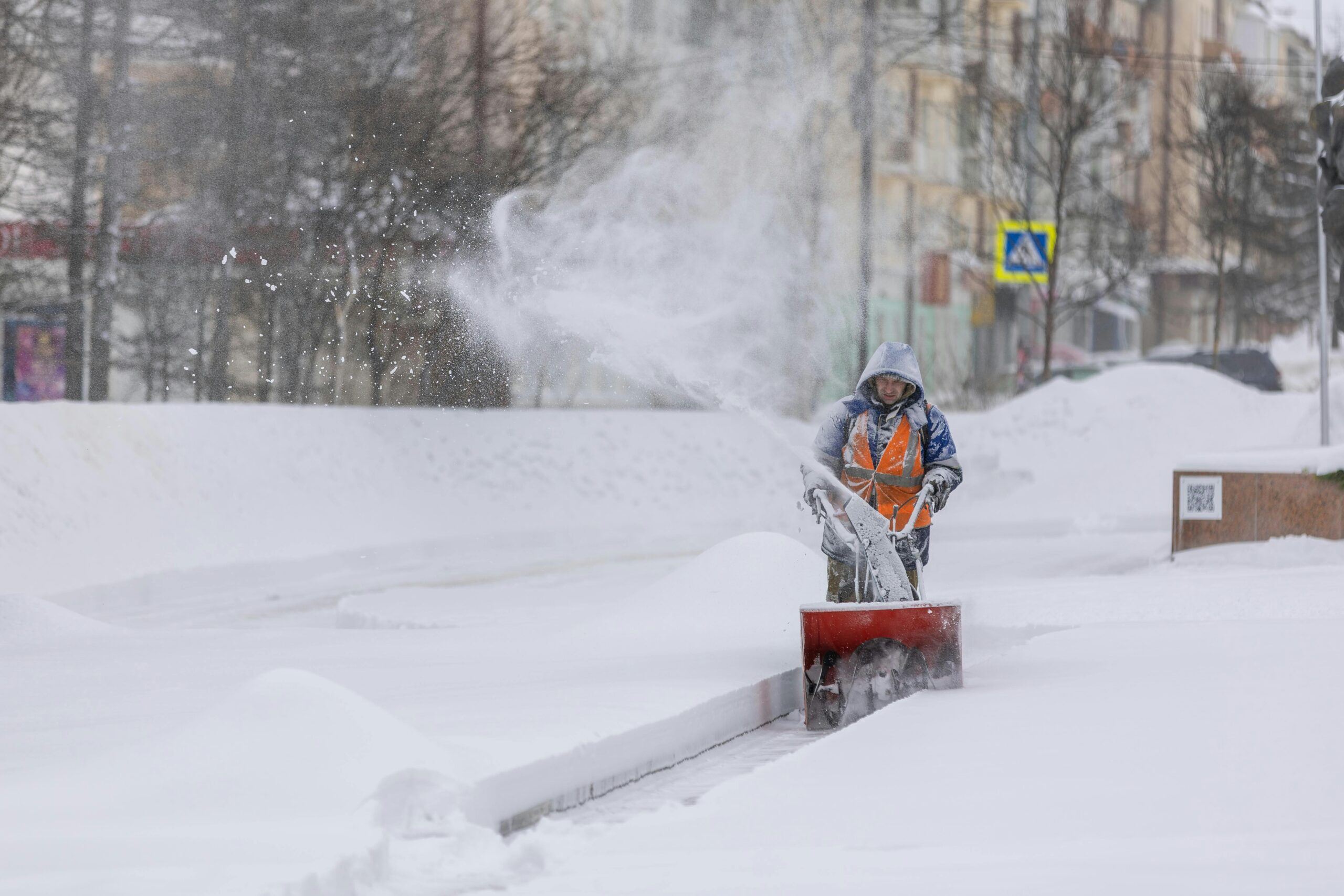 person-using-a-snow-blower-to-clear-a-city-sidewalk-during-a-heavy-winter-snowfall