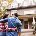 a happy couple outside looking at their new home they bought